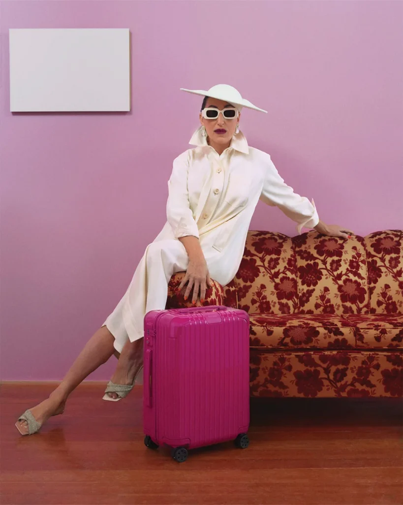 Štýlová Rossy de Palma v bielom outfite s magentovým kufrom RIMOWA.