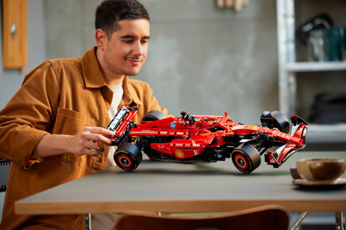 Muž skladá model pretekárskeho auta Ferrari SF-24 F1 zo stavebnice LEGO Technic 42207.