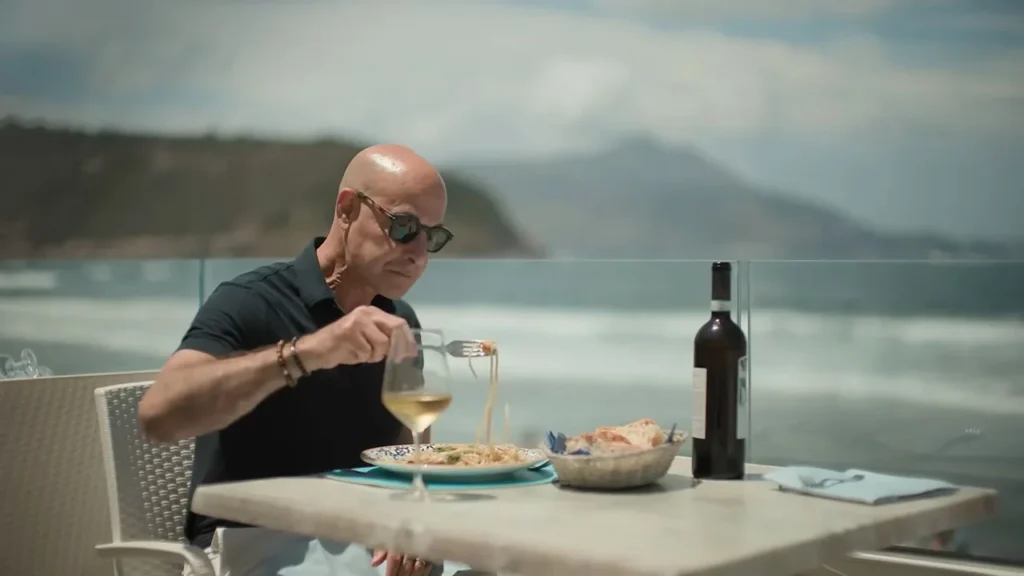 Záber z druhej série Tucci v Taliansku, kde Stanley Tucci ochutnáva cestoviny na terase pri mori.